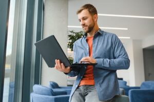 A Freelancer Man Works With A Laptop In A Work Coaching Office - AM Contabilidade